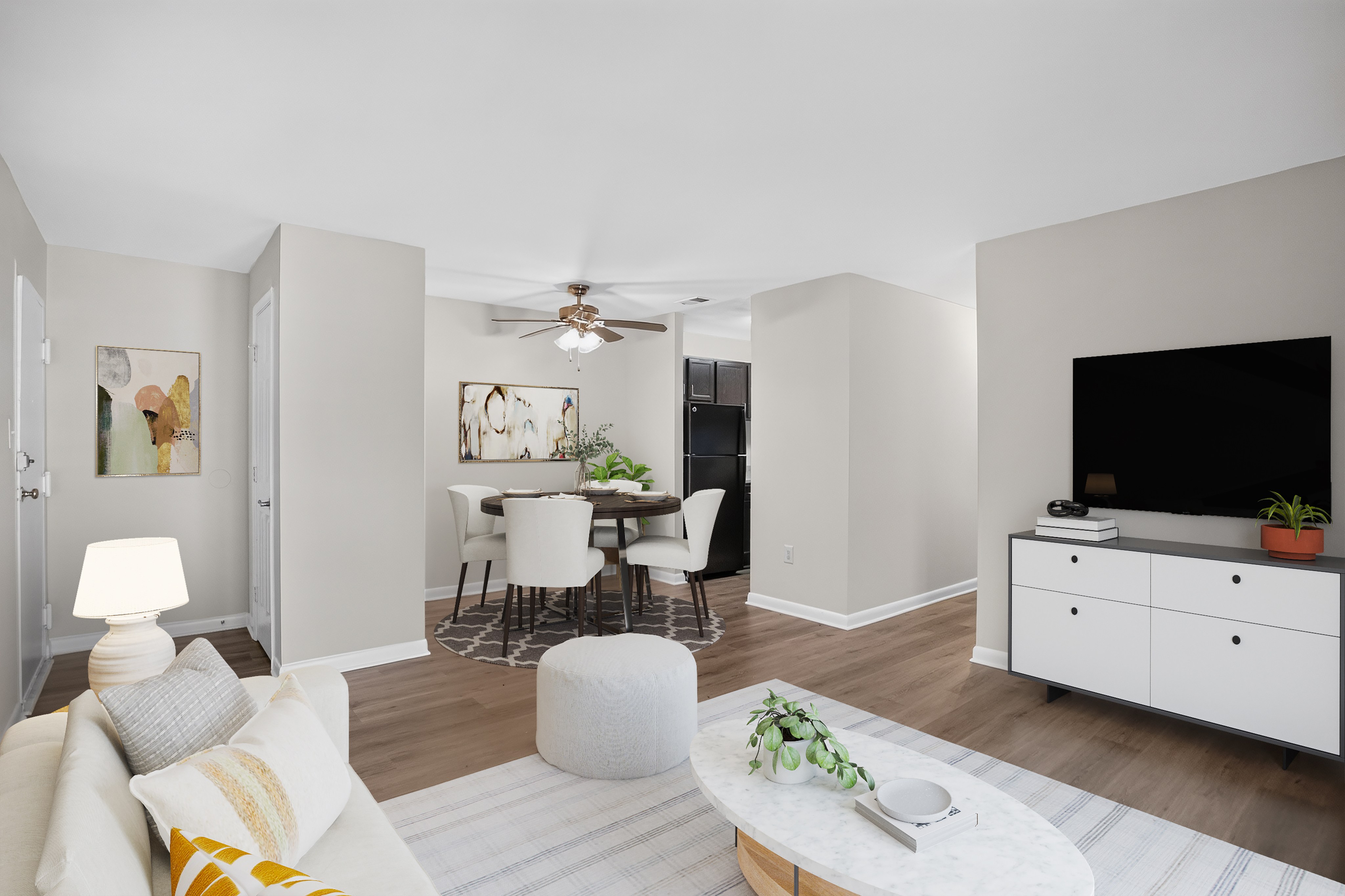 A living room with a white couch, a coffee table, and a television.